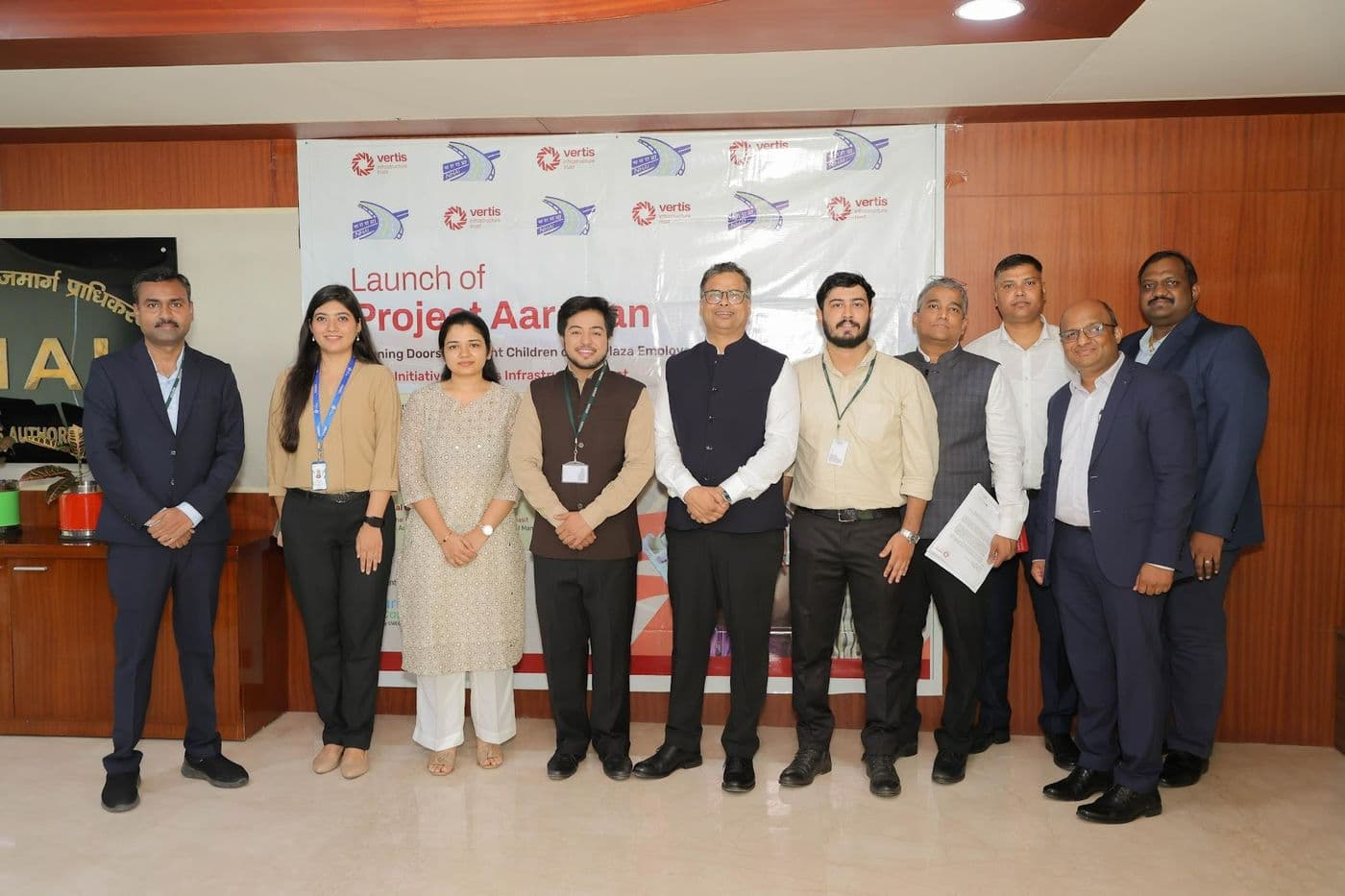 A group of attendees standing together for a photograph in front of a Project Aarohan banner in a conference room